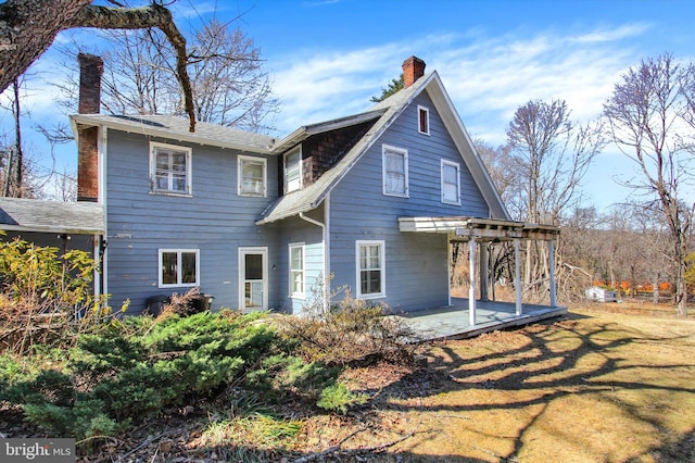 back of house featuring a yard, a patio, and a chimney