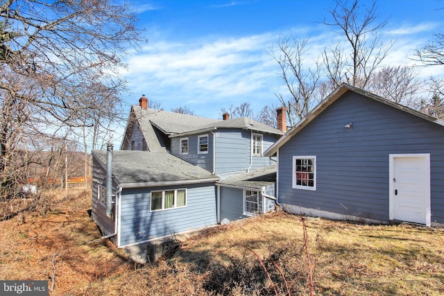 rear view of property featuring a shingled roof