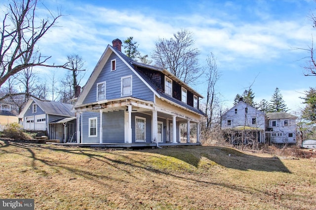 view of front of property with a porch, a chimney, and a front yard