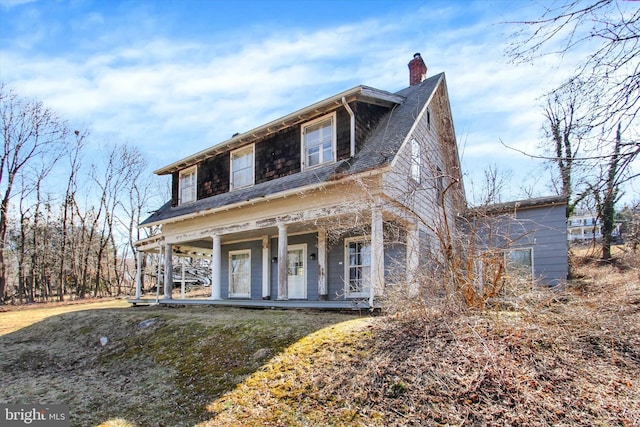 view of front of home with a porch, a chimney, and a shingled roof