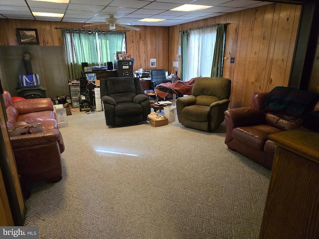 living room featuring wooden walls, carpet, and a drop ceiling