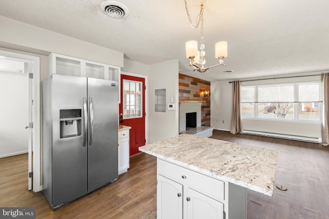 kitchen featuring white cabinets, stainless steel fridge with ice dispenser, glass insert cabinets, decorative light fixtures, and baseboard heating