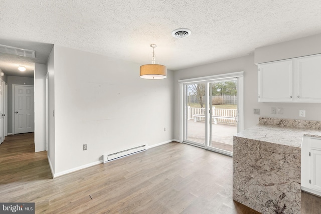 unfurnished dining area featuring a baseboard heating unit, visible vents, light wood-style flooring, and baseboards