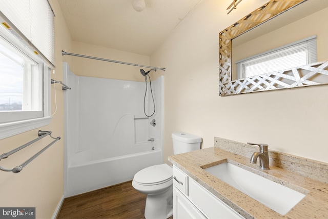 full bathroom featuring toilet, washtub / shower combination, wood finished floors, and vanity