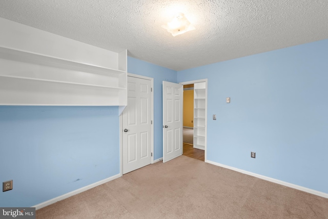 unfurnished bedroom featuring light carpet, a textured ceiling, baseboards, and a closet