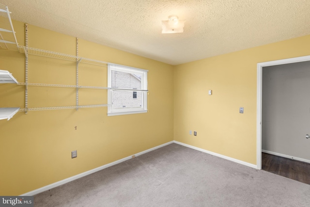 unfurnished room with a textured ceiling, carpet, and baseboards