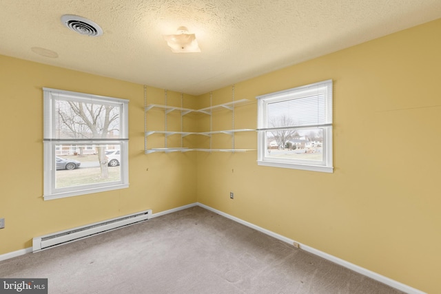 spare room featuring a textured ceiling, carpet floors, visible vents, baseboards, and baseboard heating