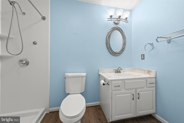 bathroom featuring toilet, baseboards, wood finished floors, and vanity