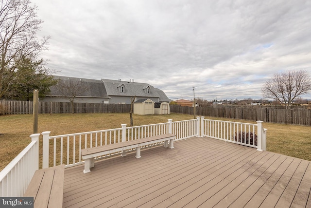 wooden deck featuring a fenced backyard, an outdoor structure, a lawn, and a shed