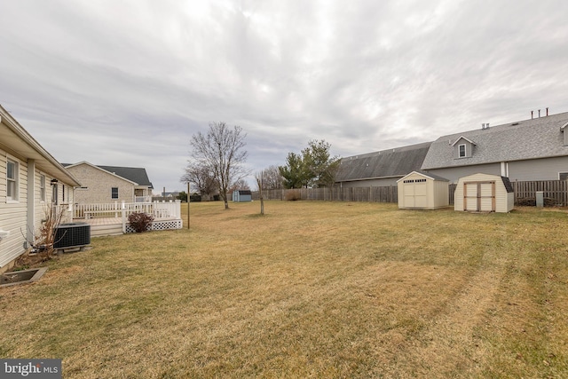 view of yard with a storage shed, an outbuilding, fence, cooling unit, and a wooden deck