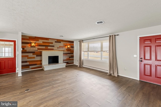 unfurnished living room with a fireplace with raised hearth, baseboard heating, dark wood finished floors, and visible vents