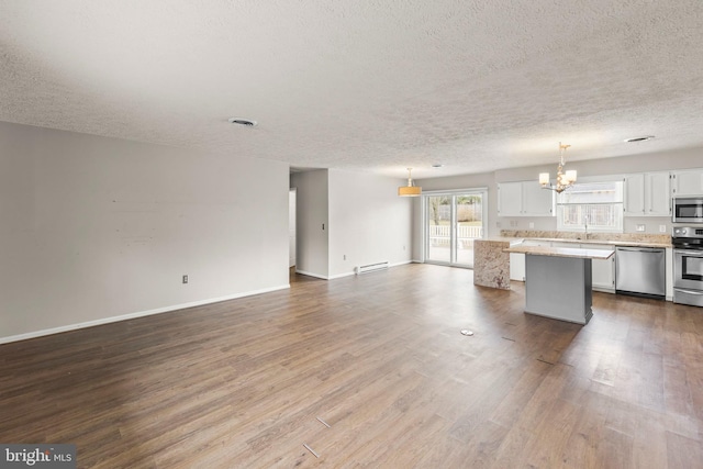 kitchen featuring white cabinets, open floor plan, appliances with stainless steel finishes, a center island, and pendant lighting