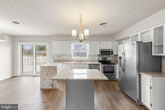 kitchen featuring hanging light fixtures, a kitchen island, white cabinets, and stainless steel appliances