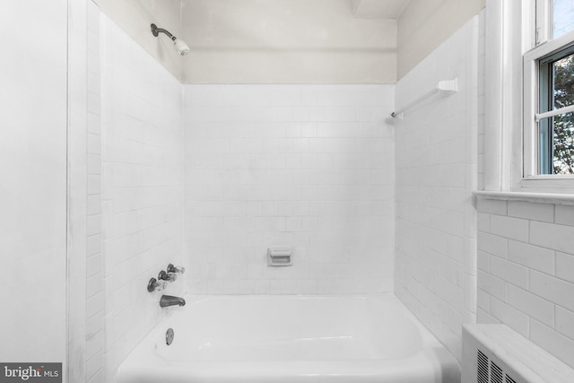 bathroom featuring radiator heating unit and tiled shower / bath