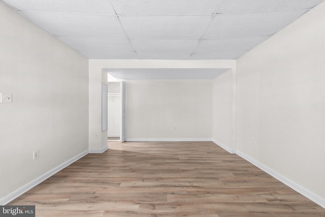 empty room with a paneled ceiling and light wood-type flooring