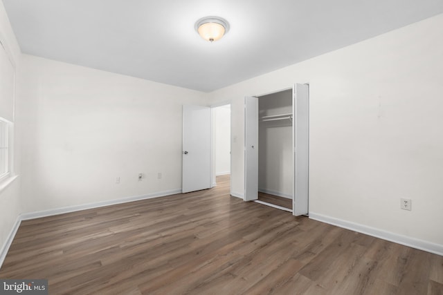 unfurnished bedroom with dark hardwood / wood-style floors and a closet