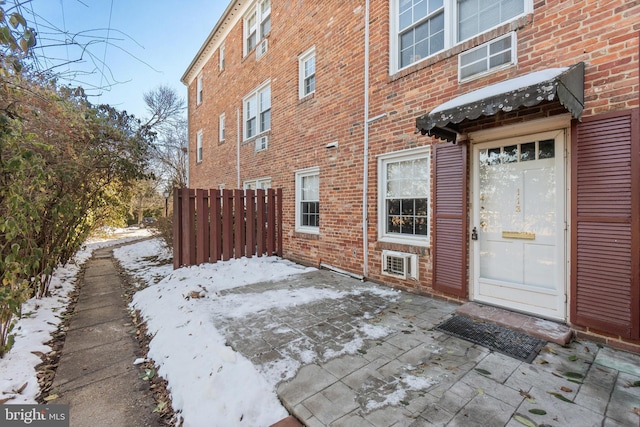 snow covered property entrance with a patio and a wall mounted air conditioner