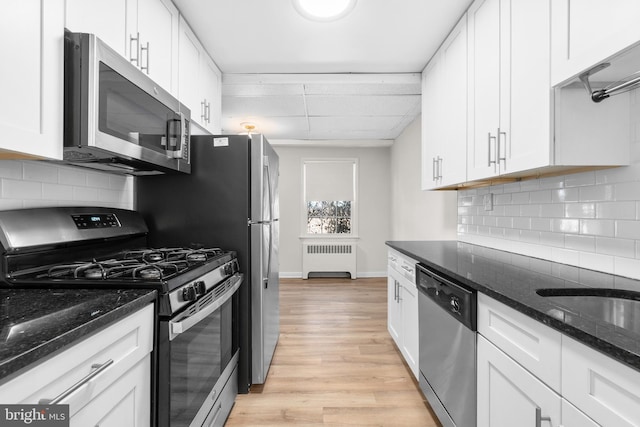 kitchen featuring appliances with stainless steel finishes, radiator, and white cabinets