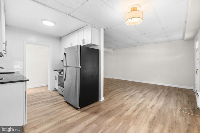 kitchen with white cabinetry, light wood-type flooring, backsplash, appliances with stainless steel finishes, and a drop ceiling