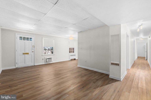 entryway featuring hardwood / wood-style flooring, an AC wall unit, radiator, and a drop ceiling