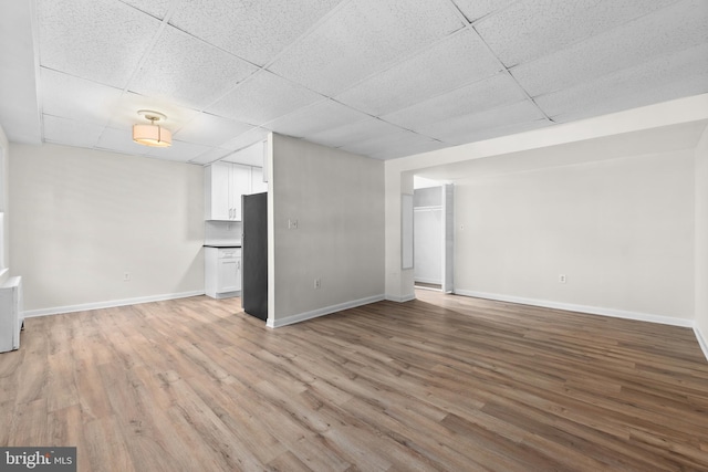 basement with stainless steel refrigerator, a paneled ceiling, and hardwood / wood-style floors