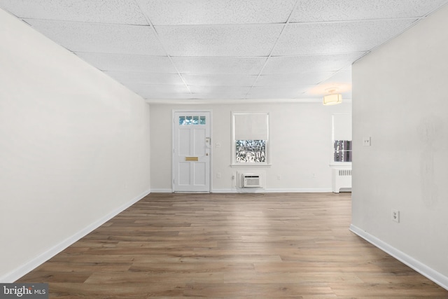 foyer with hardwood / wood-style floors, radiator, a paneled ceiling, and a wall unit AC