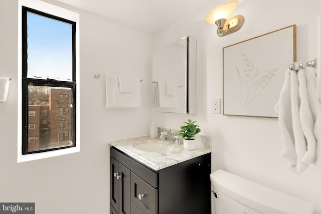 bathroom featuring vanity, plenty of natural light, and toilet