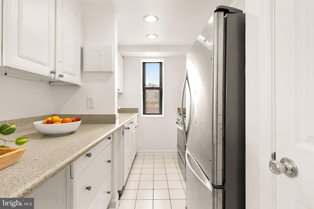 kitchen featuring white cabinetry, light tile patterned flooring, stainless steel fridge, and light stone counters