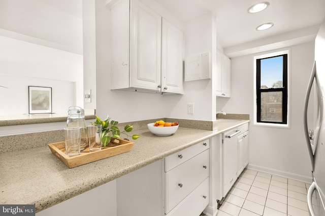 kitchen featuring light tile patterned floors, sink, white cabinets, and refrigerator