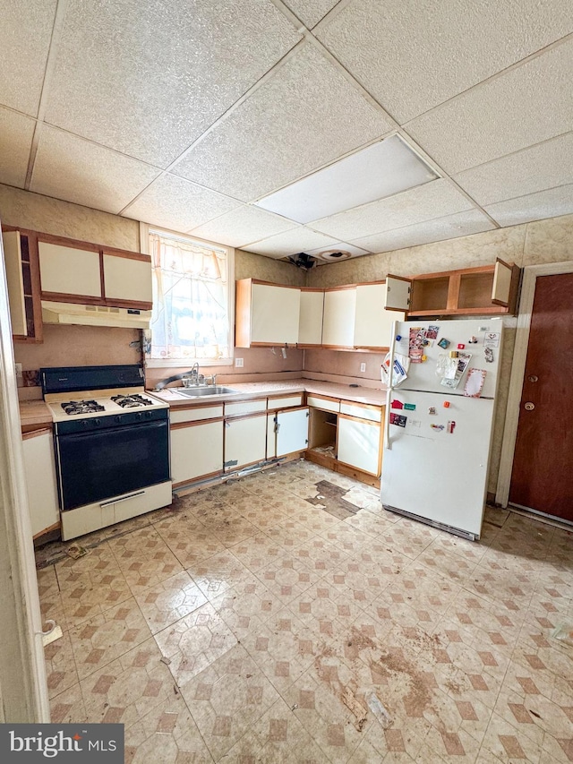 kitchen with gas range, sink, white cabinetry, a drop ceiling, and white fridge