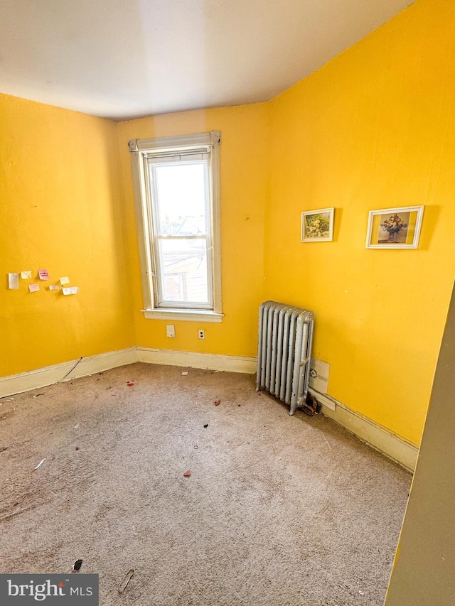 unfurnished room with radiator heating unit and carpet flooring