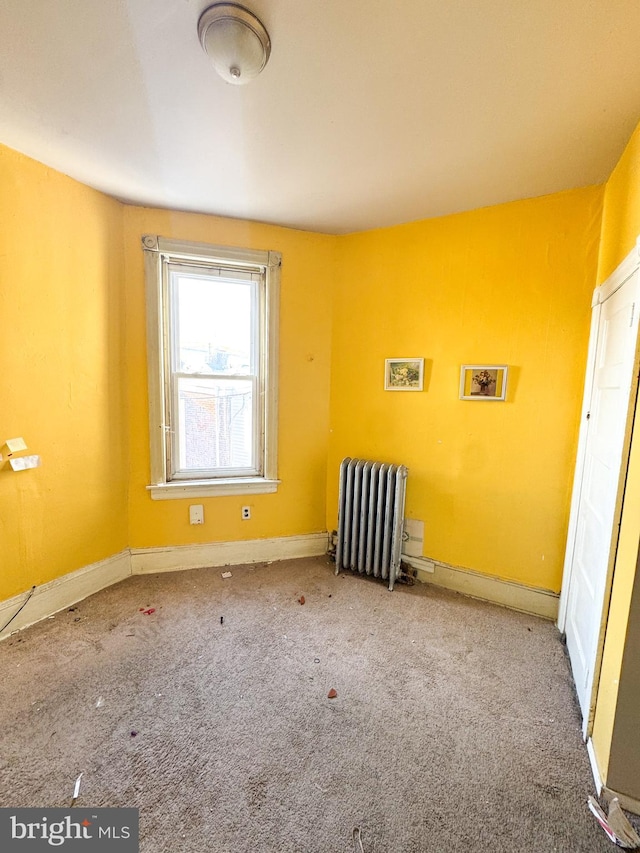 carpeted empty room featuring radiator heating unit