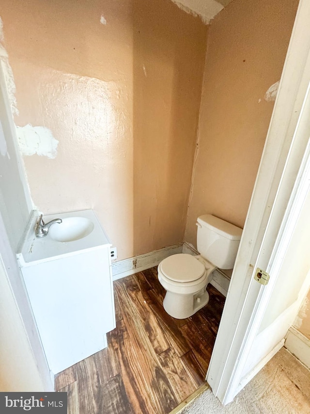 bathroom featuring wood-type flooring, toilet, and vanity