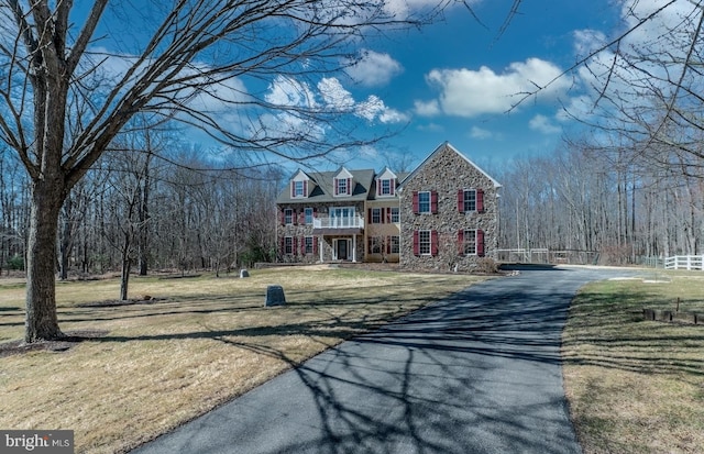 view of front of house featuring a balcony, aphalt driveway, and a front yard