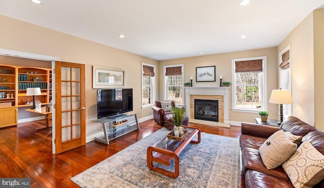 living room featuring dark wood-style floors, a glass covered fireplace, baseboards, and recessed lighting