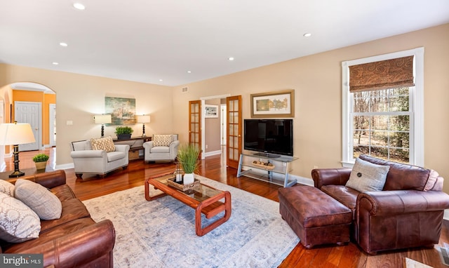 living area featuring arched walkways, wood finished floors, and recessed lighting