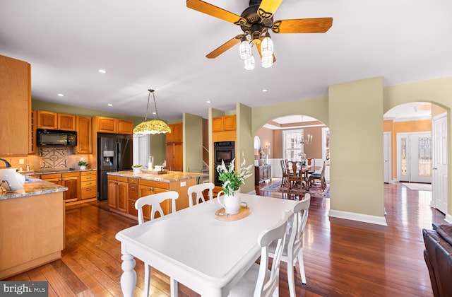 dining room with arched walkways, dark wood-style flooring, baseboards, and recessed lighting