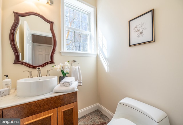 bathroom with baseboards, vanity, and toilet