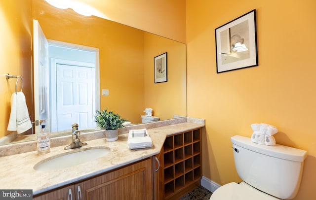 half bath featuring toilet, baseboards, and vanity