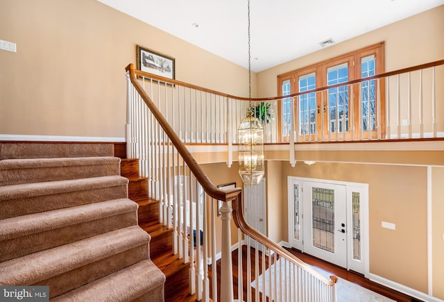 stairway featuring visible vents, an inviting chandelier, and wood finished floors