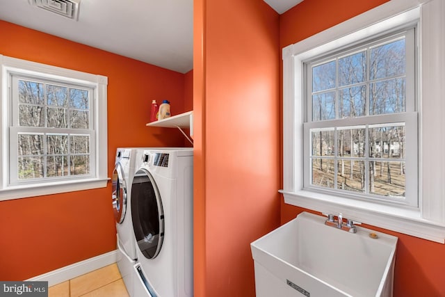 clothes washing area featuring light tile patterned floors, laundry area, a sink, visible vents, and independent washer and dryer