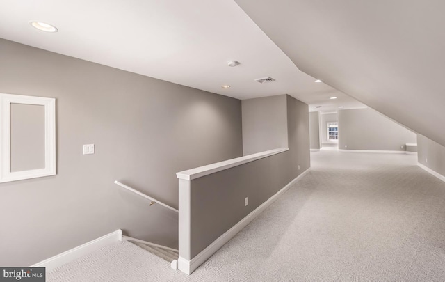 hallway featuring baseboards, visible vents, carpet flooring, and an upstairs landing