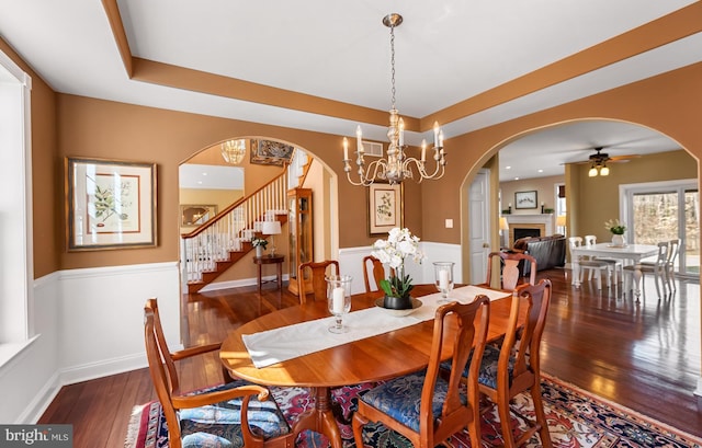 dining space featuring stairway, a fireplace, a raised ceiling, and hardwood / wood-style flooring