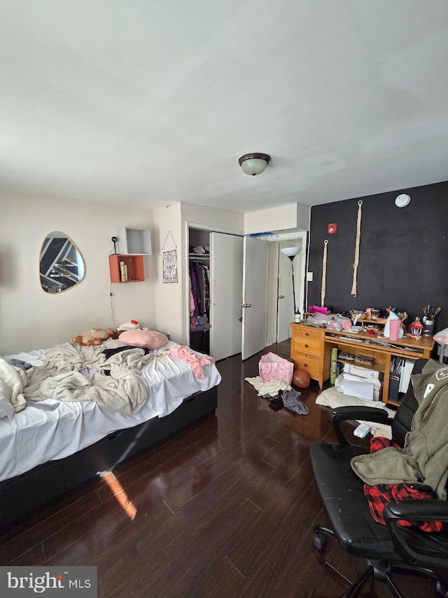 bedroom with dark hardwood / wood-style flooring and a closet