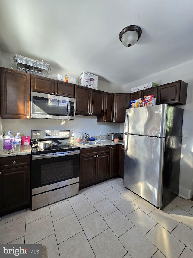 kitchen featuring dark brown cabinetry, appliances with stainless steel finishes, sink, and light tile patterned floors