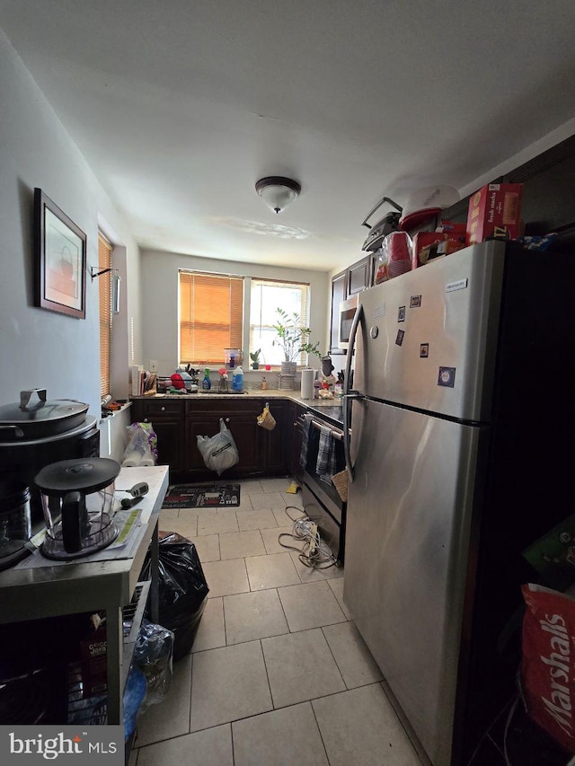 kitchen featuring dark brown cabinetry, light tile patterned flooring, and appliances with stainless steel finishes