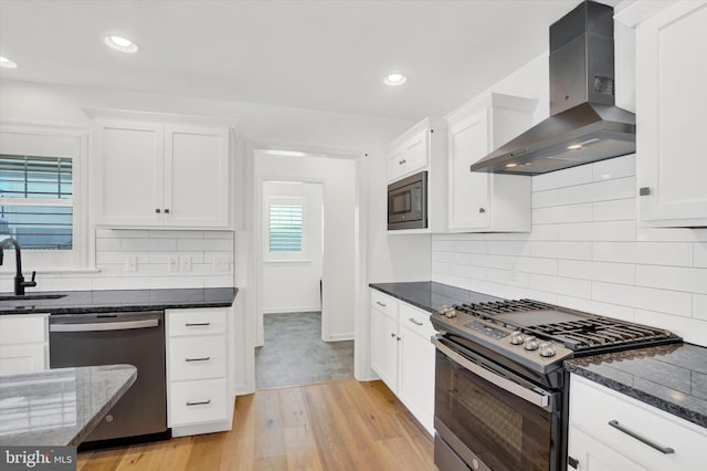 kitchen featuring light hardwood / wood-style flooring, white cabinetry, backsplash, stainless steel appliances, and wall chimney exhaust hood