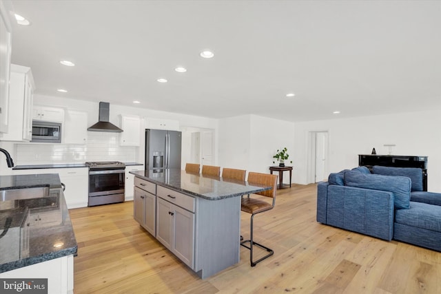 kitchen with stainless steel appliances, white cabinetry, sink, and wall chimney exhaust hood