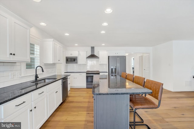 kitchen featuring white cabinets, a center island, wall chimney exhaust hood, and appliances with stainless steel finishes