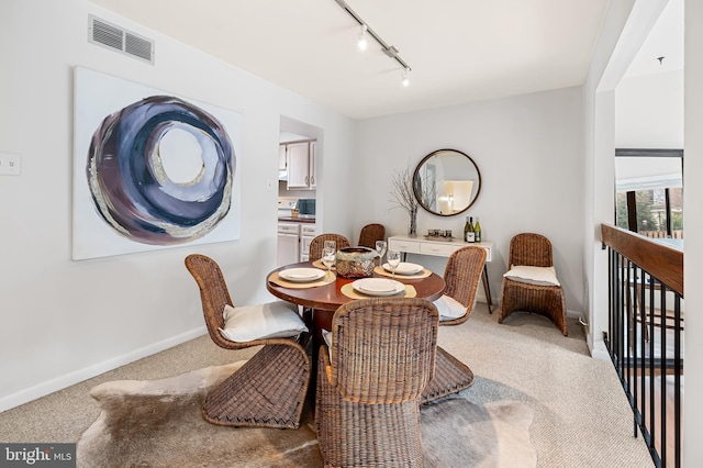 carpeted dining room featuring track lighting